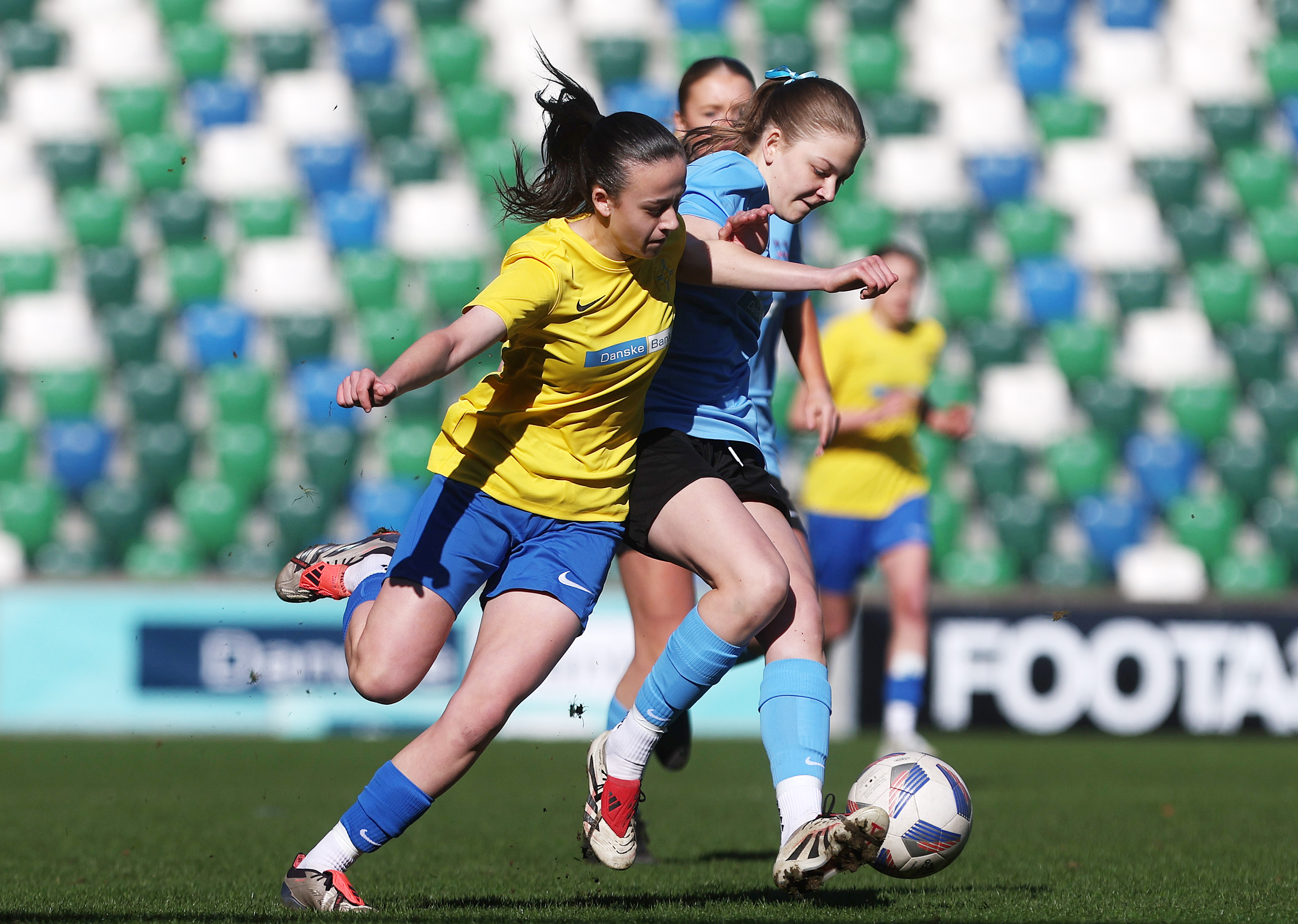 Two players compete for the ball during a NISFA final