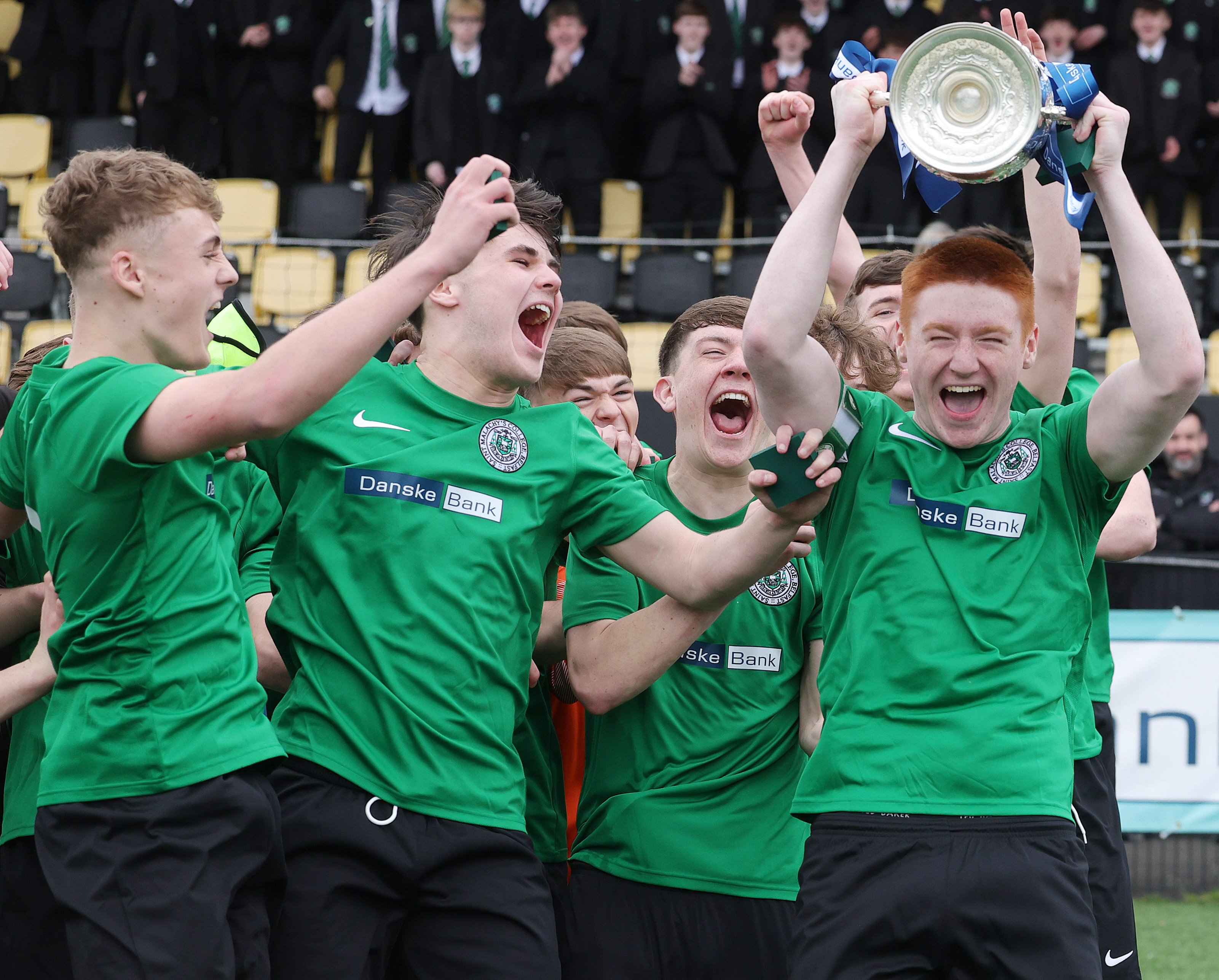 St Malachy's College players lift the trophy
