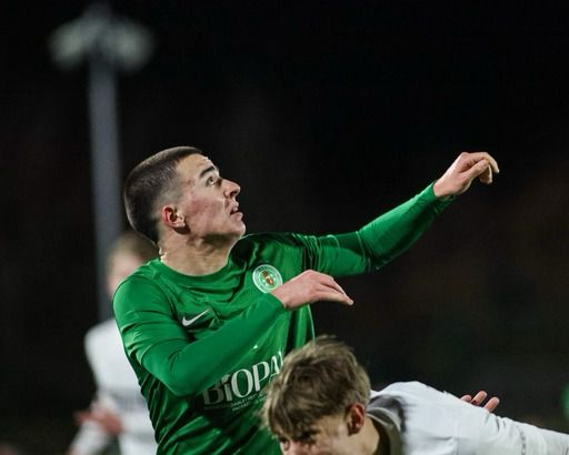 A Northern Ireland schools' player reaches for a high ball under floodlights